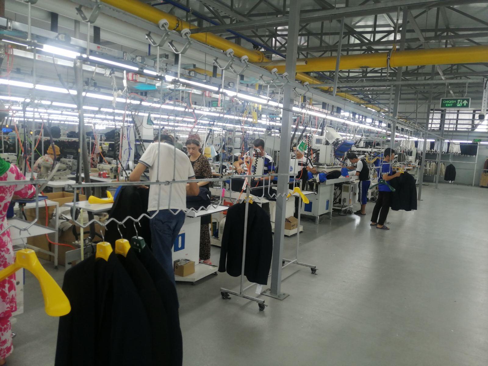 Production floor with garment workers and jackets on hanging rails